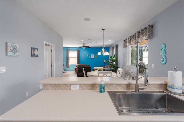 kitchen with pendant lighting, a ceiling fan, a sink, open floor plan, and light countertops