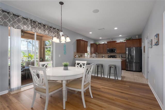 dining room with light wood finished floors, a chandelier, recessed lighting, and baseboards