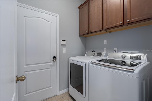 washroom with washer and dryer, light tile patterned floors, cabinet space, and baseboards