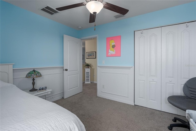 bedroom with a wainscoted wall, a closet, visible vents, and carpet floors