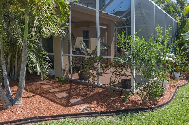 view of side of property featuring glass enclosure and stucco siding