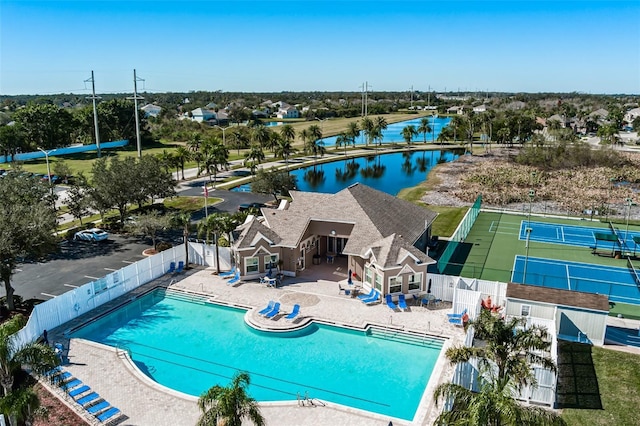 community pool with a patio, a fenced backyard, and a water view