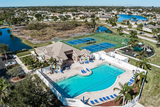 community pool with a patio area, a residential view, fence, and a water view