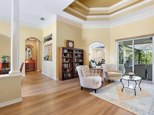 living room with ceiling fan, visible vents, arched walkways, and light wood-style flooring