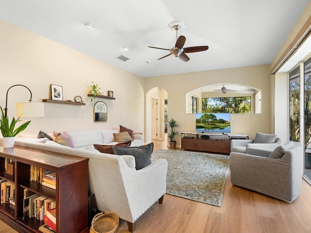 living room with ceiling fan, visible vents, arched walkways, and wood finished floors