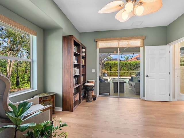 sitting room featuring baseboards, light wood-type flooring, a wealth of natural light, and ceiling fan