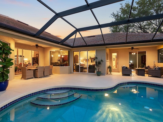 outdoor pool featuring outdoor lounge area, glass enclosure, a patio area, and ceiling fan