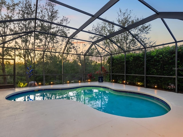 pool at dusk with an outdoor pool, a patio, and a lanai