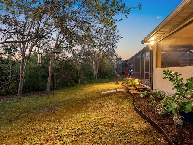 yard at dusk featuring a lanai