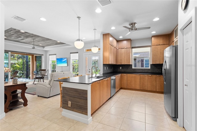 kitchen featuring visible vents, dark countertops, open floor plan, stainless steel appliances, and a sink