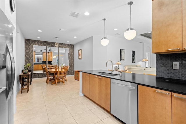 kitchen featuring stainless steel appliances, dark countertops, visible vents, and a sink