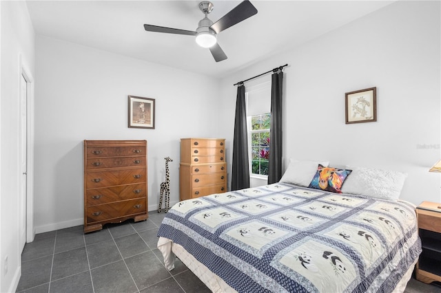 bedroom with ceiling fan, baseboards, and dark tile patterned flooring