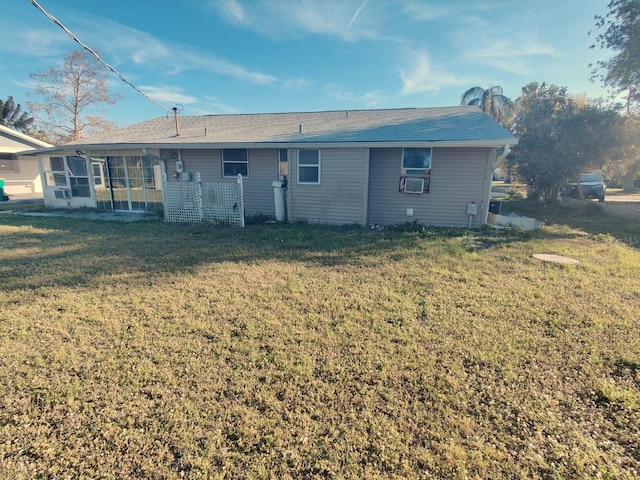 rear view of property with cooling unit, a sunroom, and a yard