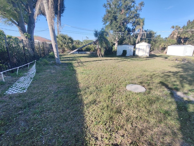 view of yard with an outbuilding, a storage unit, and fence