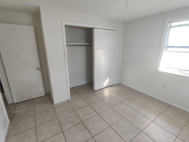 unfurnished bedroom featuring light tile patterned floors, a closet, and baseboards