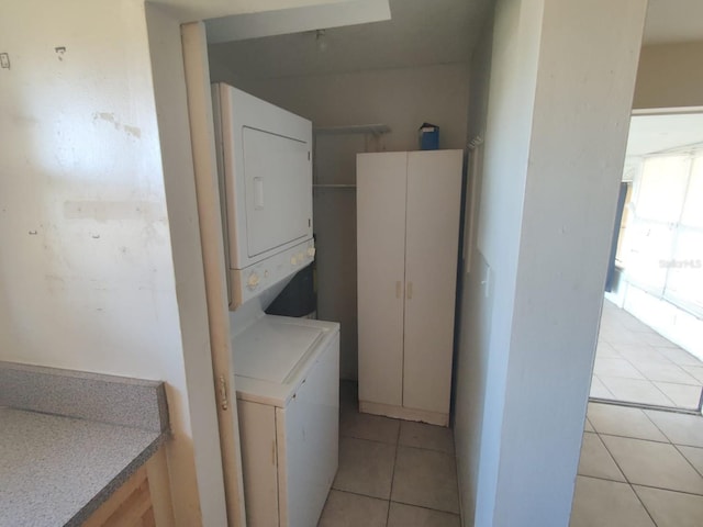 laundry room with stacked washer / drying machine and light tile patterned floors