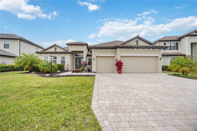 view of front of home with a garage, a tile roof, decorative driveway, a front yard, and stucco siding