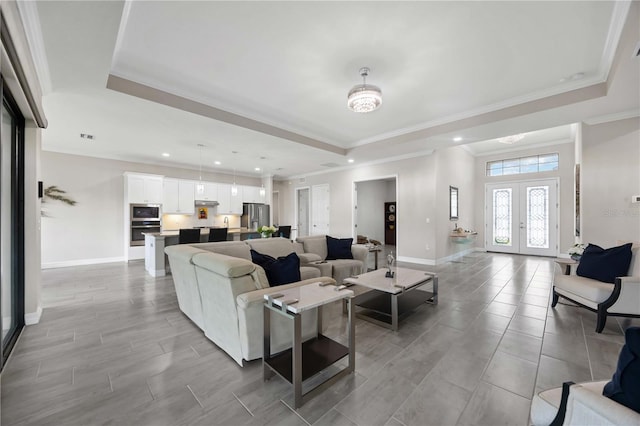 living room featuring ornamental molding, french doors, a raised ceiling, and baseboards