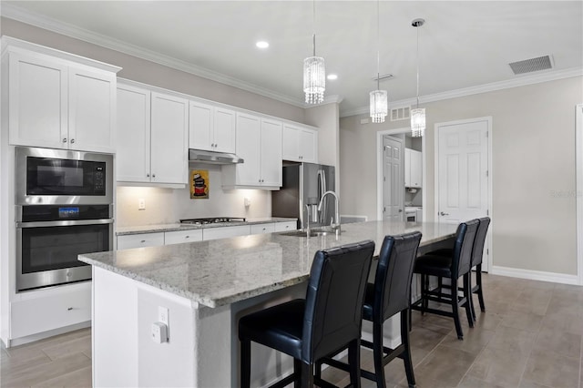 kitchen featuring stainless steel appliances, visible vents, white cabinets, a sink, and a large island with sink