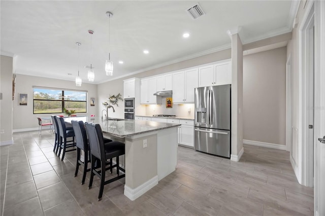 kitchen with stainless steel appliances, visible vents, white cabinets, a sink, and an island with sink