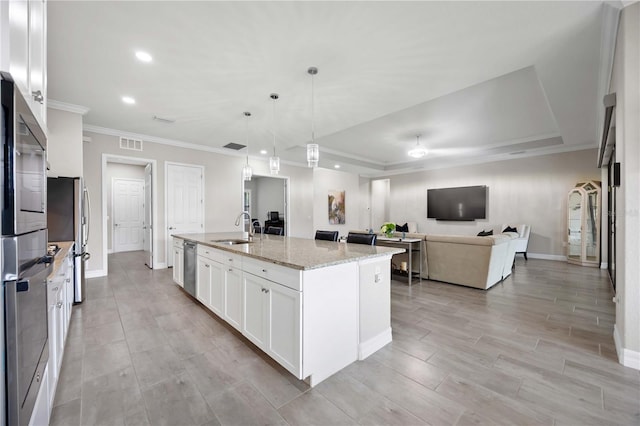 kitchen featuring light stone counters, stainless steel appliances, a sink, visible vents, and white cabinets