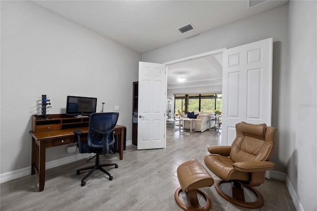 office area with light wood-style floors, baseboards, and visible vents