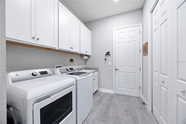 laundry room with washing machine and dryer, cabinet space, a sink, and baseboards