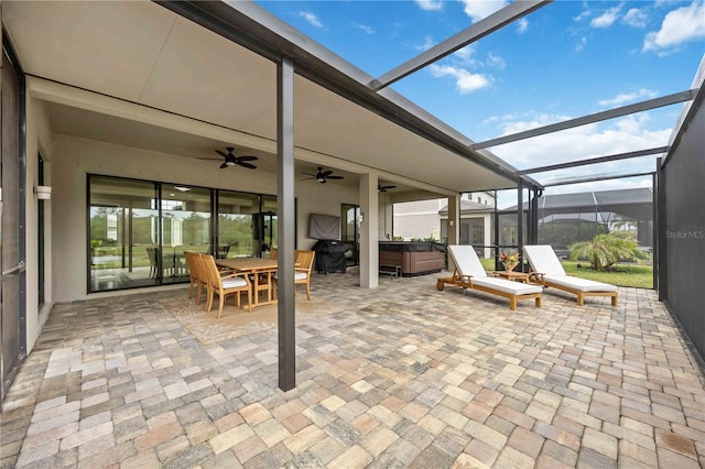 view of patio / terrace with ceiling fan, glass enclosure, outdoor dining area, and a hot tub