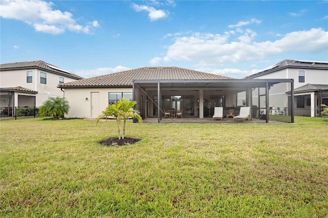 rear view of house with a tile roof, fence, a yard, stucco siding, and a patio area