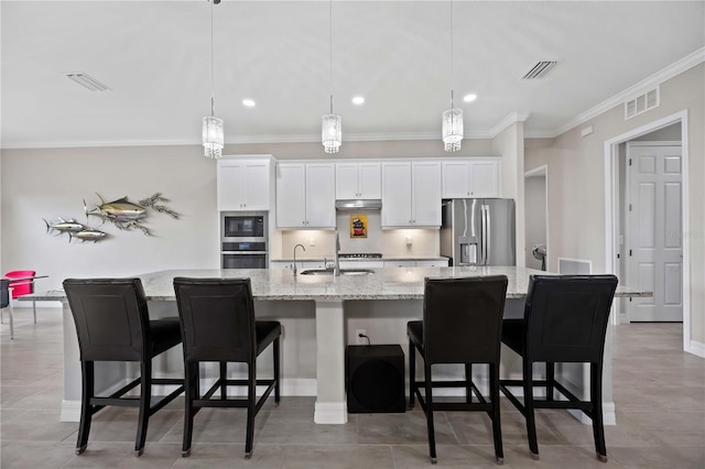 kitchen with appliances with stainless steel finishes, a spacious island, under cabinet range hood, ornamental molding, and white cabinets