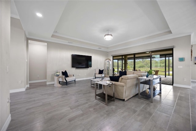 living room with a tray ceiling, ornamental molding, and baseboards