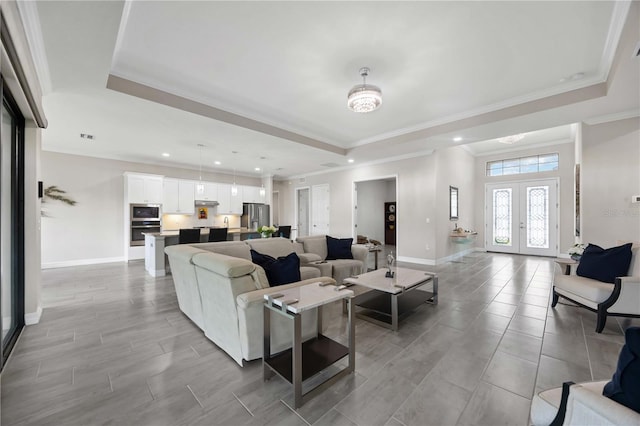 living area featuring a raised ceiling, baseboards, recessed lighting, crown molding, and french doors