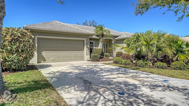 view of front of house featuring a tile roof, driveway, an attached garage, and stucco siding