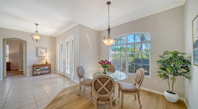 dining area featuring arched walkways, french doors, crown molding, light tile patterned floors, and baseboards