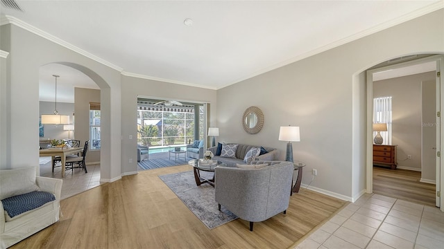 living room with light wood-type flooring, baseboards, visible vents, and ornamental molding