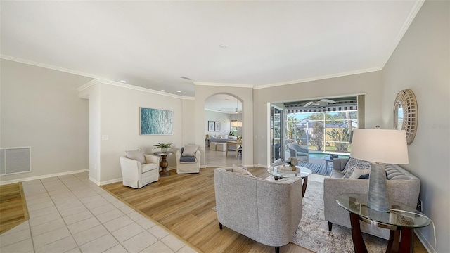 living area with light tile patterned floors, ornamental molding, visible vents, and baseboards