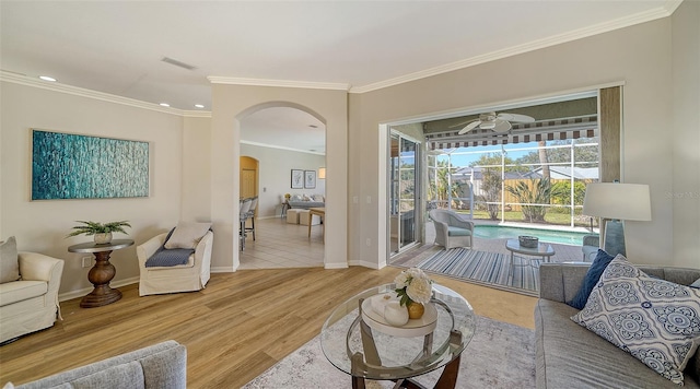 living area featuring arched walkways, visible vents, a sunroom, wood finished floors, and baseboards