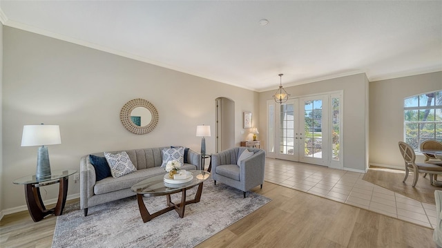 living area featuring light wood-style flooring, arched walkways, baseboards, and ornamental molding