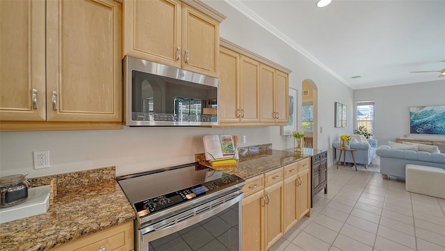 kitchen featuring light brown cabinets, arched walkways, stainless steel appliances, and open floor plan