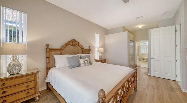 bedroom with visible vents, light wood-style flooring, ensuite bathroom, and multiple windows