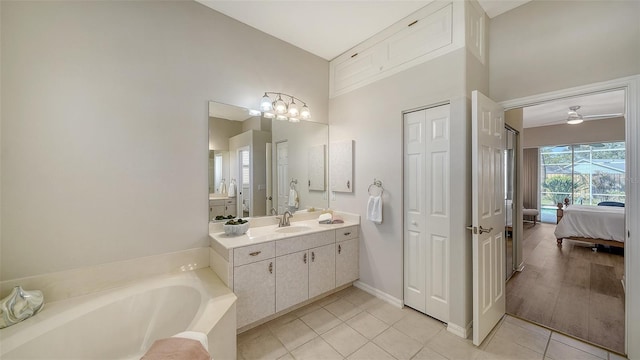 ensuite bathroom featuring connected bathroom, tile patterned floors, a garden tub, vanity, and a closet