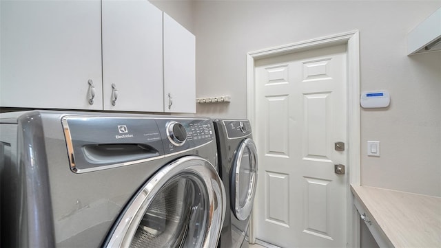 clothes washing area featuring separate washer and dryer and cabinet space