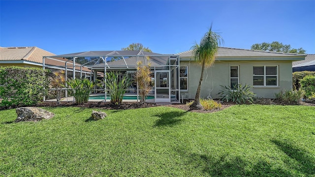 back of property with glass enclosure, a lawn, an outdoor pool, and stucco siding