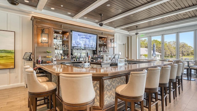 bar with wooden ceiling, a decorative wall, a community bar, light wood-style floors, and beamed ceiling