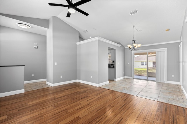 empty room with lofted ceiling, ceiling fan with notable chandelier, wood finished floors, visible vents, and baseboards