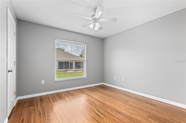 spare room featuring ceiling fan, a textured ceiling, baseboards, and hardwood / wood-style floors