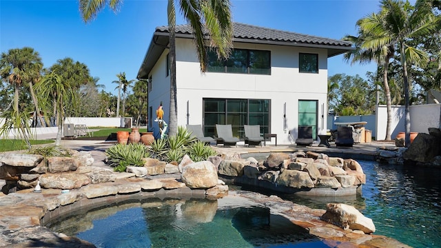 back of property with a tiled roof, a patio area, fence, and stucco siding