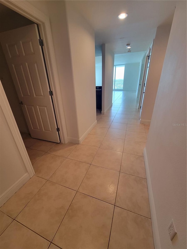 hallway with light tile patterned floors, recessed lighting, and baseboards