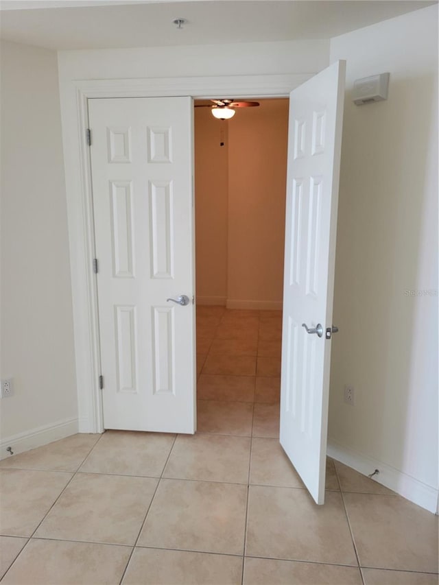 hall featuring light tile patterned floors and baseboards