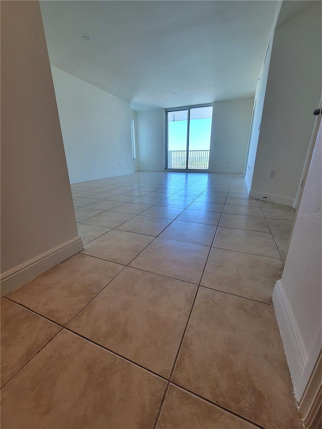 empty room featuring light tile patterned floors and baseboards